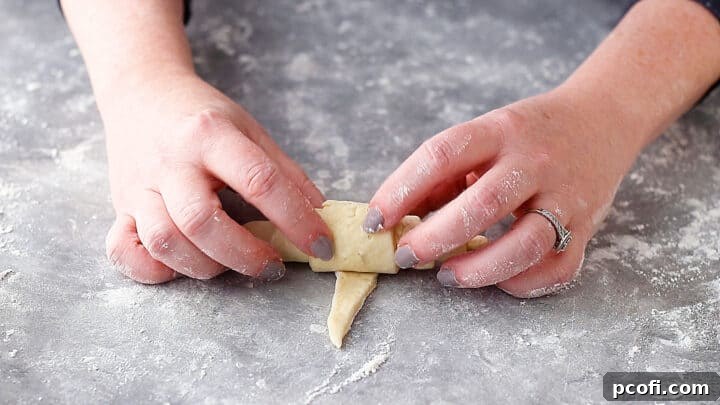 Rolling croissant dough from the wide end to the point.
