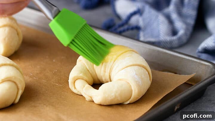 Brushing croissants with egg wash.