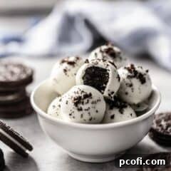 Delicious Oreo balls in a white bowl, coated in white chocolate and garnished with Oreo crumbs, ready to be enjoyed.