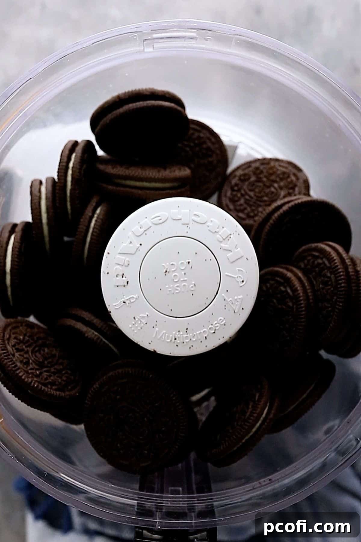 Whole Oreo cookies being placed into a food processor, ready to be crushed into fine crumbs.