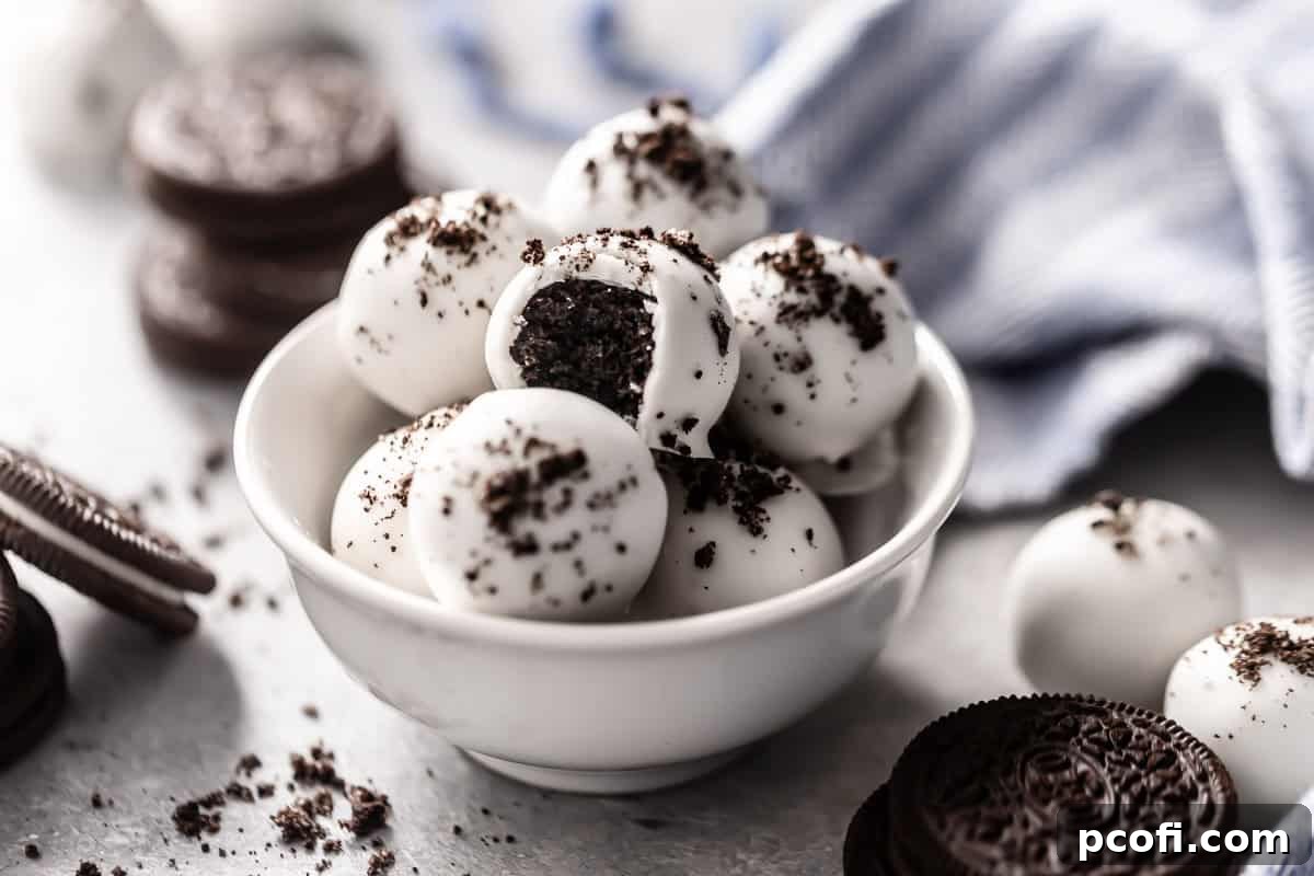 A bowl filled with finished Oreo truffle balls, elegantly coated in chocolate and generously topped with a sprinkle of crushed Oreo crumbs.
