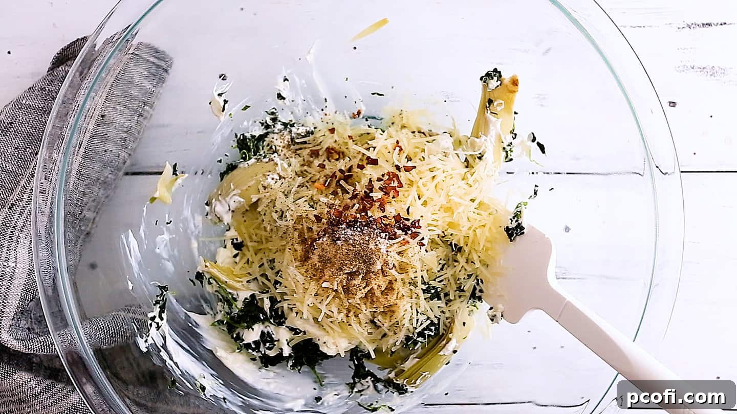 Adding grated Parmesan cheese and a medley of seasonings to the spinach artichoke dip mixture.