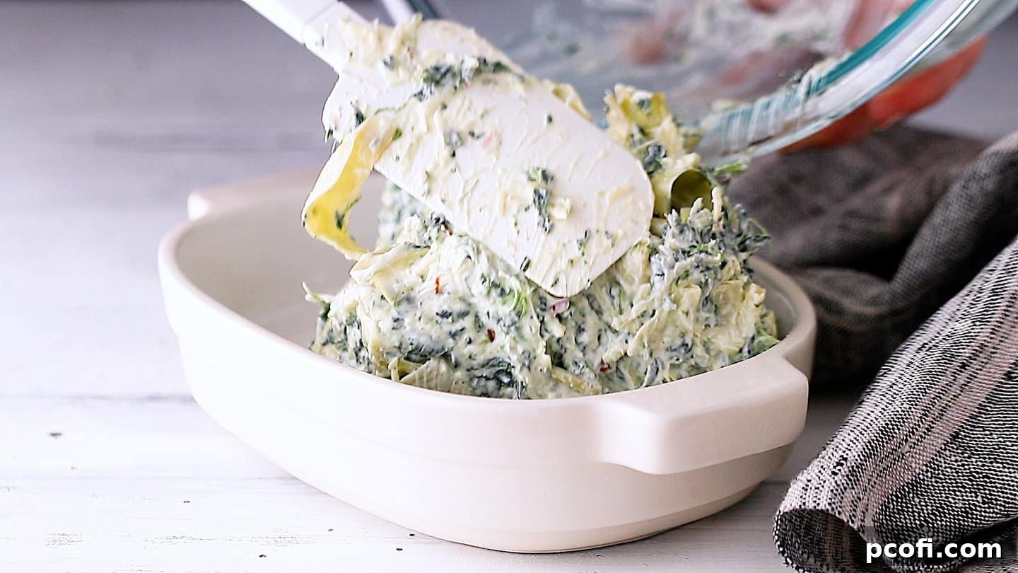 Transferring the prepared spinach artichoke dip mixture into an oven-safe baking dish for baking.