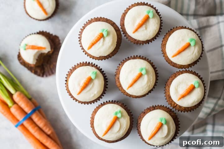 A beautiful top-down arrangement of several carrot cake cupcakes on a cake stand, surrounded by fresh, vibrant carrots and a cozy plaid cloth, emphasizing a rustic and homemade aesthetic.