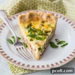 A slice of quiche Lorraine on a china plate with a green printed napkin.