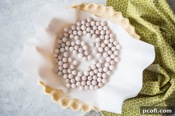 Blind-baking a pie crust in a ceramic pie dish, lined with parchment paper and filled with ceramic pie weights.