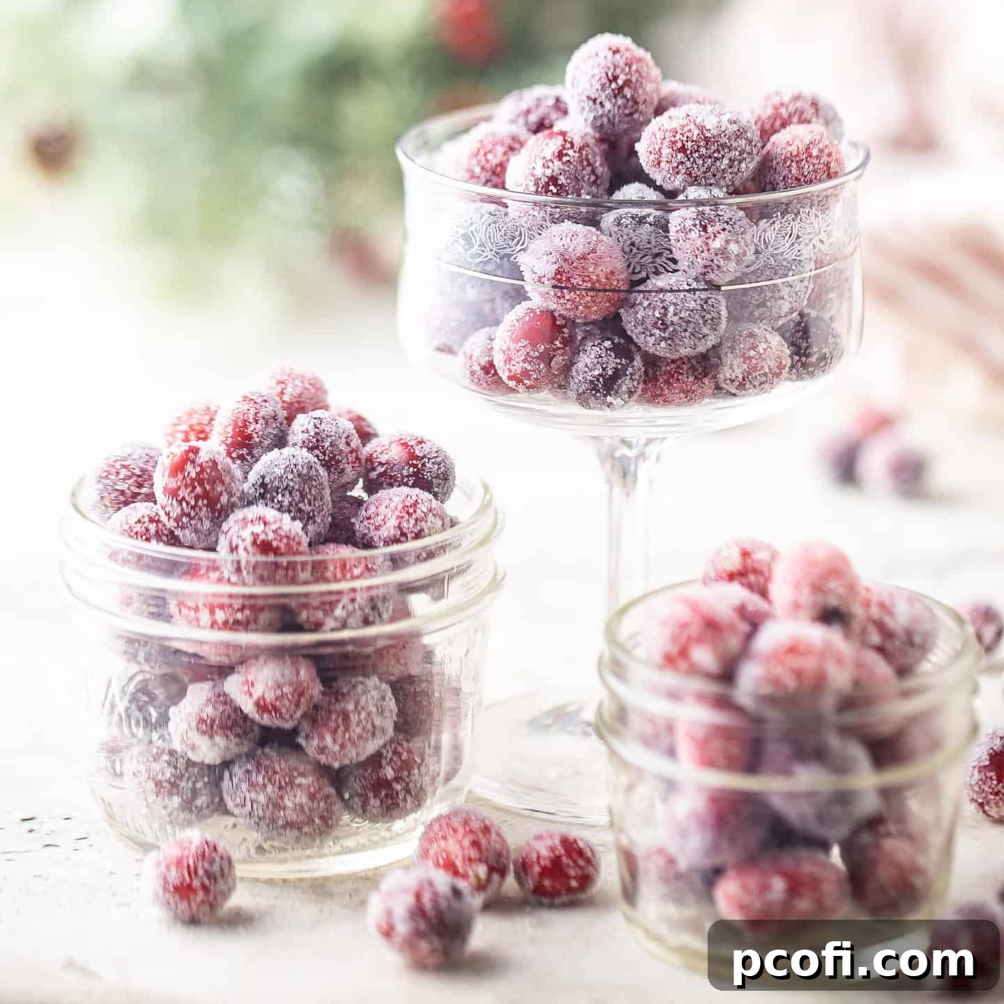 Sparkling sugared cranberries displayed in various sized glass bowls, creating a festive visual.