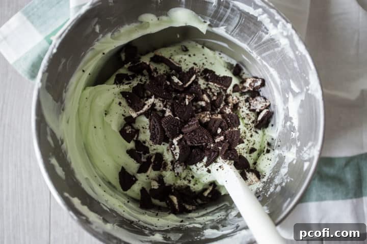 Grasshopper pie filling with crushed oreos in a stainless mixing bowl.