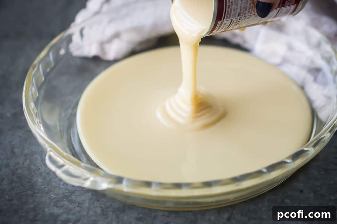 Pouring sweetened condensed milk into a glass pie dish.