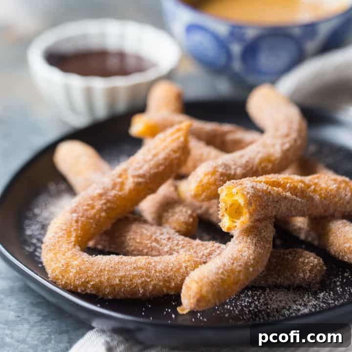 Crisp and golden homemade churros elegantly arranged on a dark plate, with luscious chocolate sauce and rich dulce de leche in the background, ready for dipping.