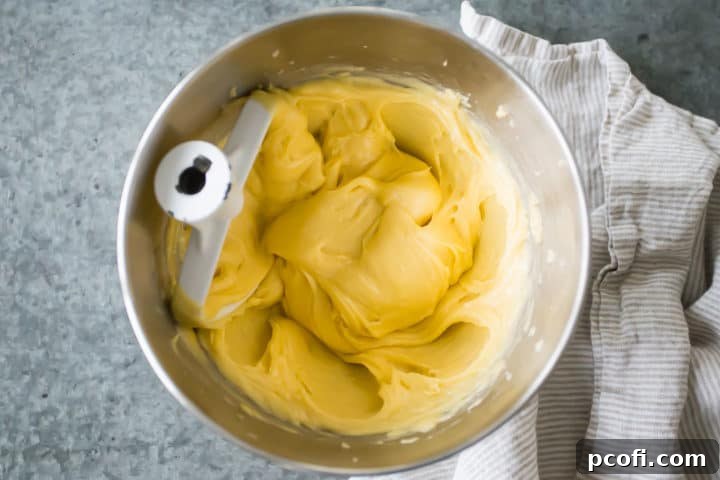 A perfectly smooth and elastic choux pastry dough for making churros sits ready in a mixing bowl, showcasing the ideal consistency achieved after incorporating all the eggs.
