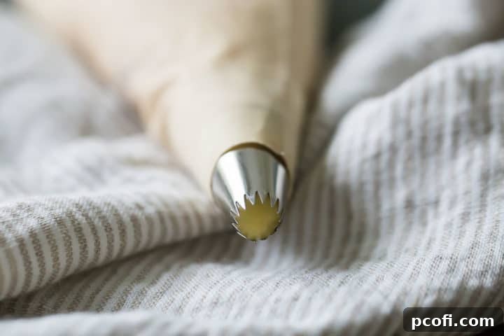 Thick churro batter is loaded into a durable pastry bag, fitted with a jumbo French star tip, poised and ready for piping into hot oil to create perfectly ridged churros.