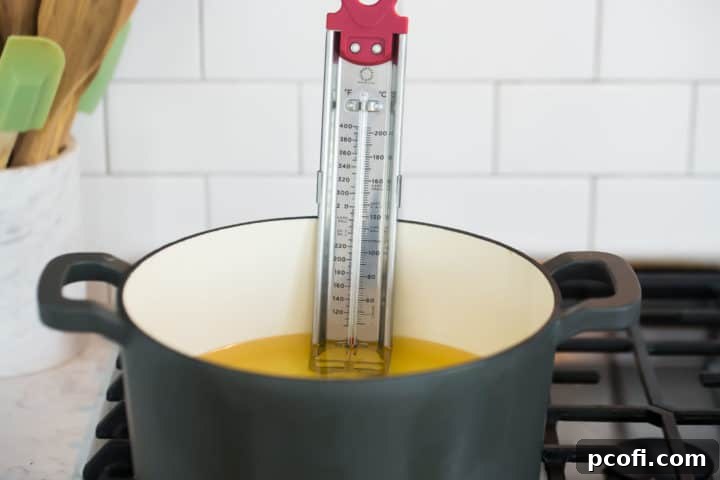 A pristine enameled cast-iron Dutch oven, perfectly sized for deep frying, sits empty and ready on a stovetop, highlighting the essential equipment for making homemade churros.