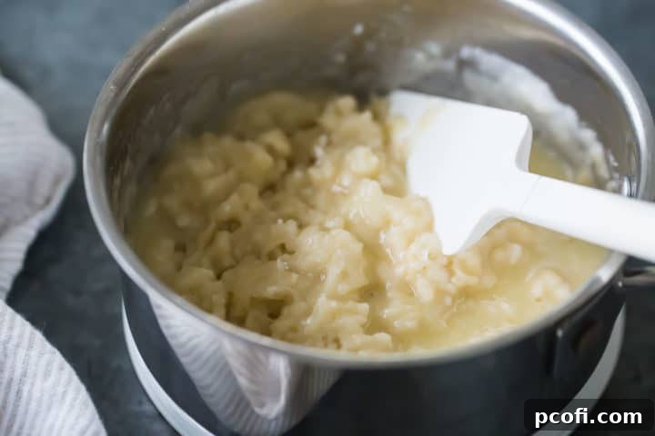 The flour and liquid are vigorously stirred together in the pot, transforming into a smooth, cohesive roux—the crucial cooked paste for choux pastry, the foundation of perfect churros.