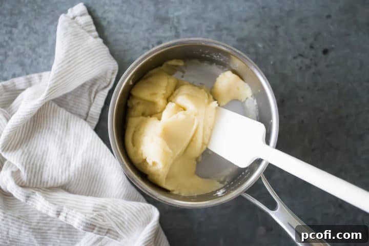 The smooth, cooked choux pastry roux sits in a small pot, having gathered into a single mass, indicating it's perfectly prepared for the next stage of churro dough creation.