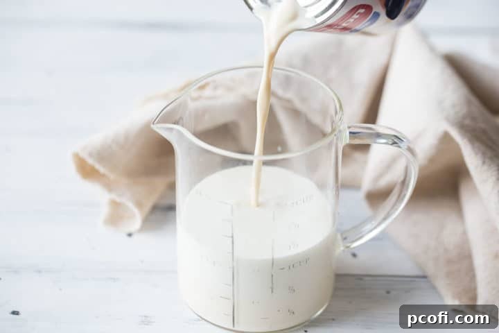 Pouring evaporated milk into a measuring cup for tres leches cake.