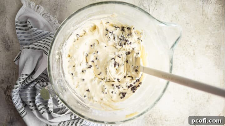 Chocolate chip cake batter in a large glass mixing bowl.