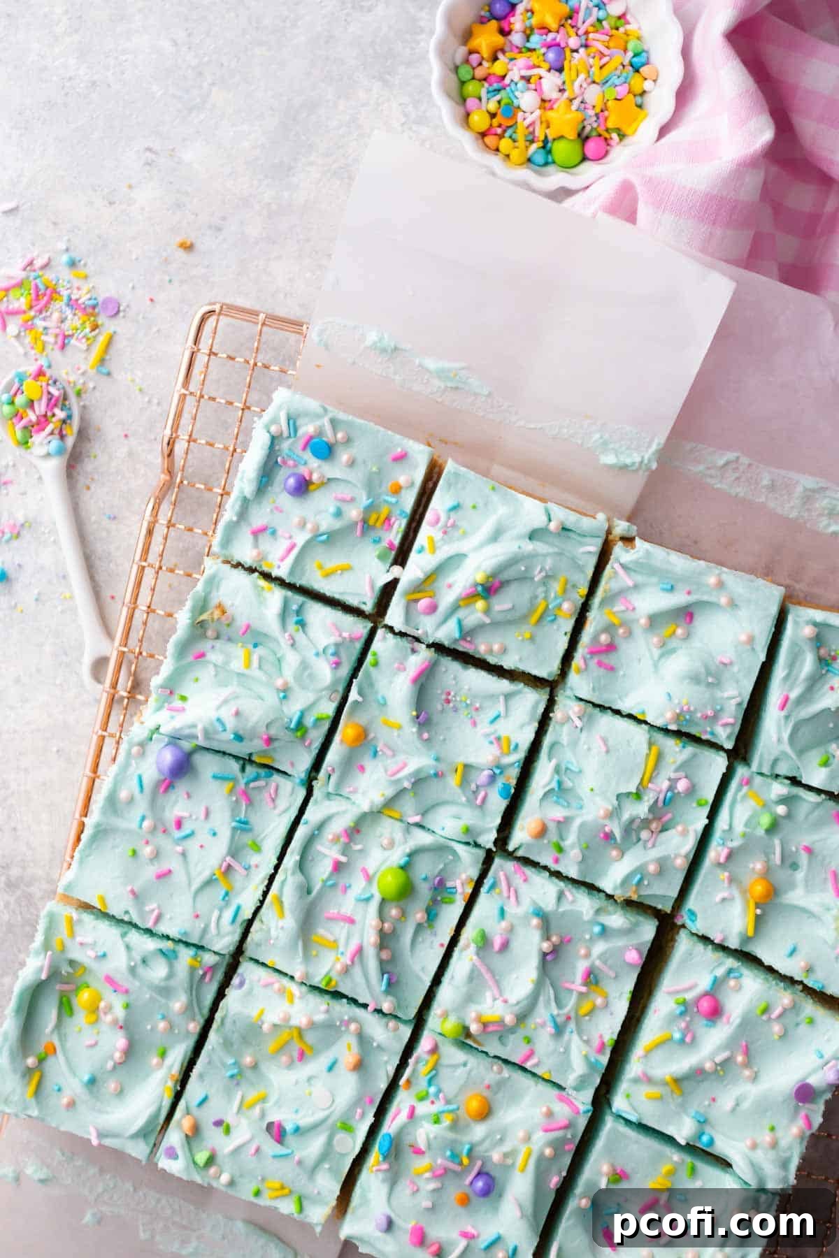 Frosted sugar cookie bars with rainbow sprinkles, cut into perfect squares and arranged on a plate.