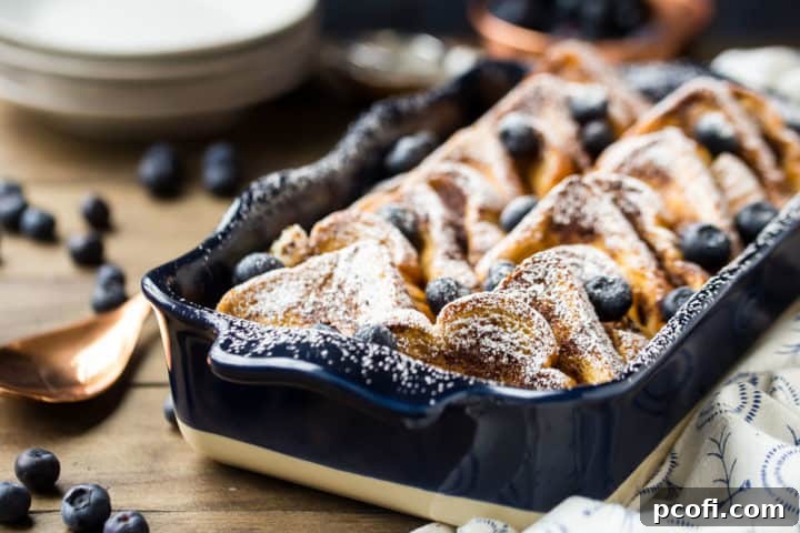 Fresh baked overnight French toast bake in a blue dish with blueberries.