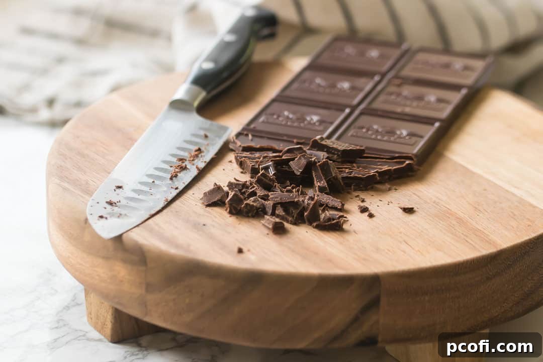 Finely chopping chocolate on a wooden cutting board to ensure even melting.