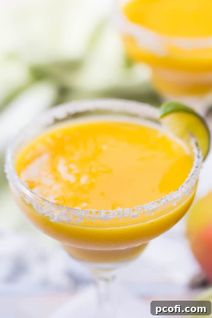 A mesmerizing close-up of beautifully blended frozen mango margaritas, showing their frosty texture and vibrant color, ready to be enjoyed.