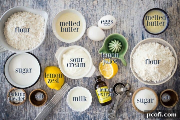 A beautifully arranged selection of fresh ingredients for making lemon muffins, including flour, sugar, baking powder, salt, lemons, butter, sour cream, milk, and eggs, all neatly labeled for clarity.