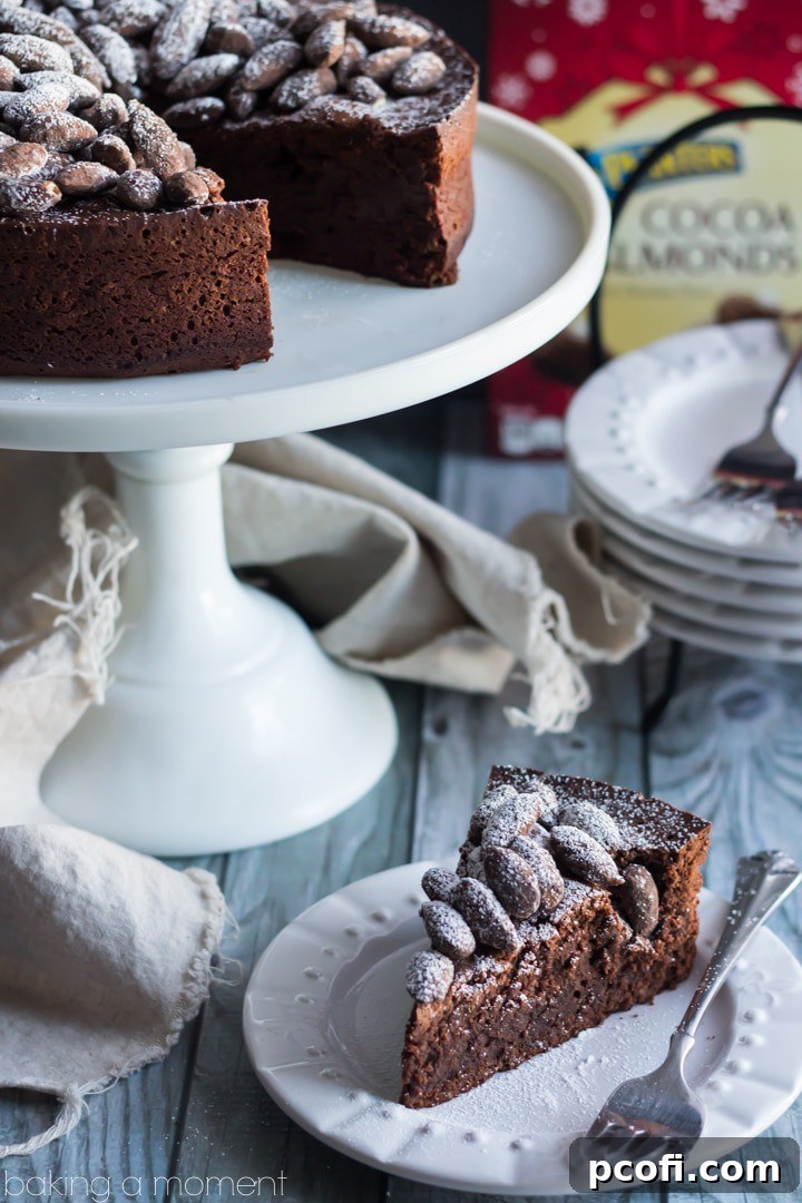 Close-up of a generous slice of Chocolate Amaretto Torte garnished with cocoa almonds and powdered sugar. #decadentdessert #homemadecake #bakingperfection