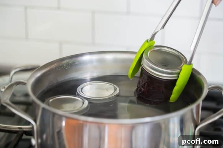 Submerging jars of homemade jam in boiling water to process.
