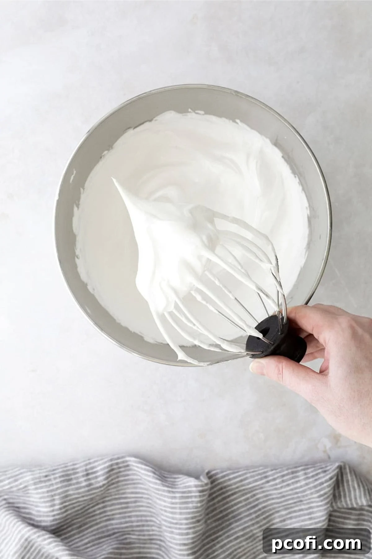 Finished marshmallow frosting, stiff and glossy, clinging to a whisk.