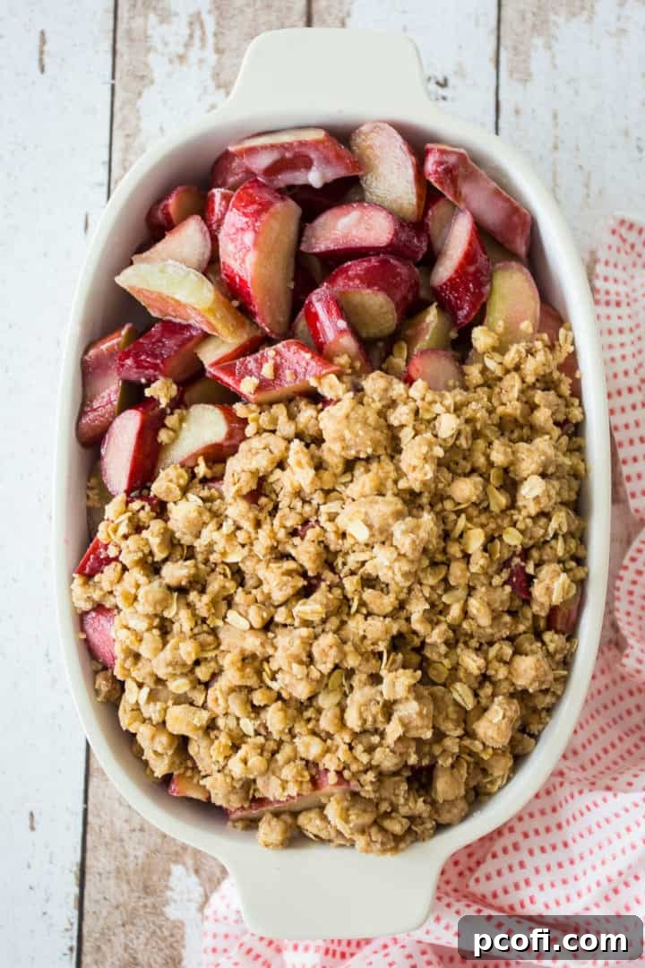 Covering rhubarb crisp filling with crumb topping.