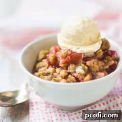 Small bowl of rhubarb crisp with a scoop of vanilla ice cream, on a pink printed napkin.