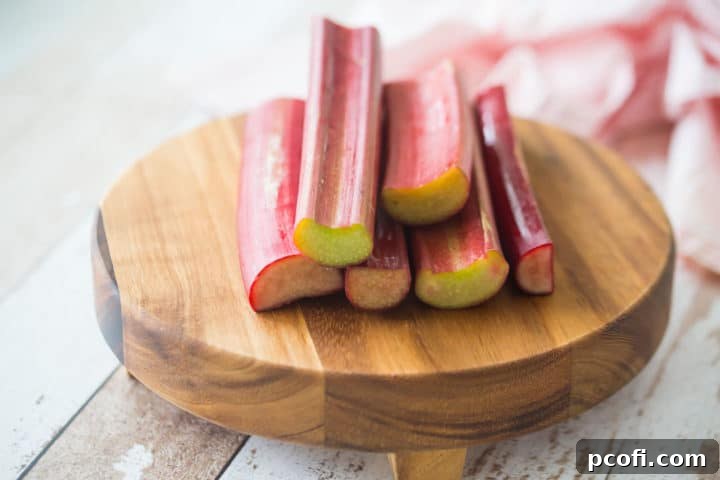 Stalks of fresh rhubarb on a wooden cutting board.