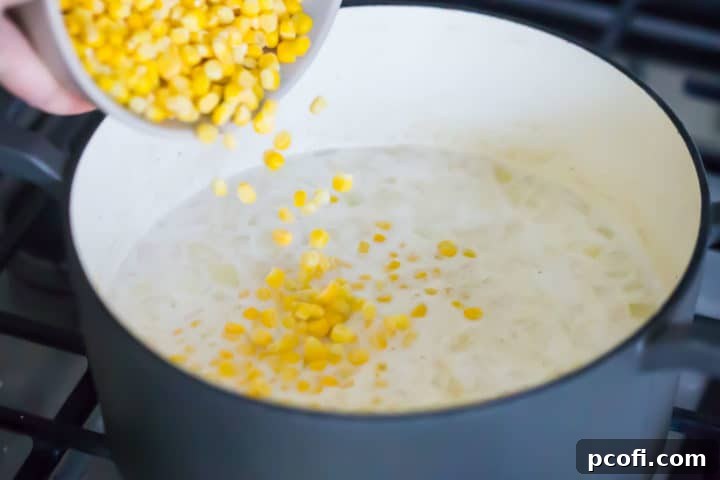 Adding corn to a pot of homemade corn chowder.