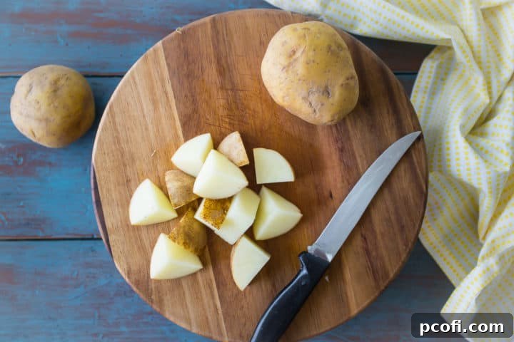Roughly chopped potatoes on a wooden cutting board.