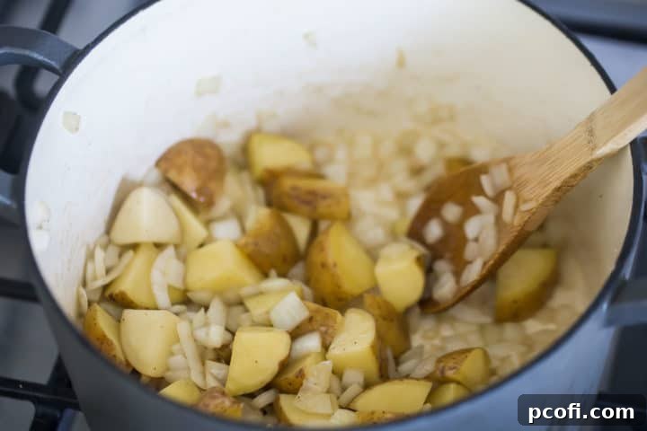 Chopped onion and potatoes cooking in a large pot.