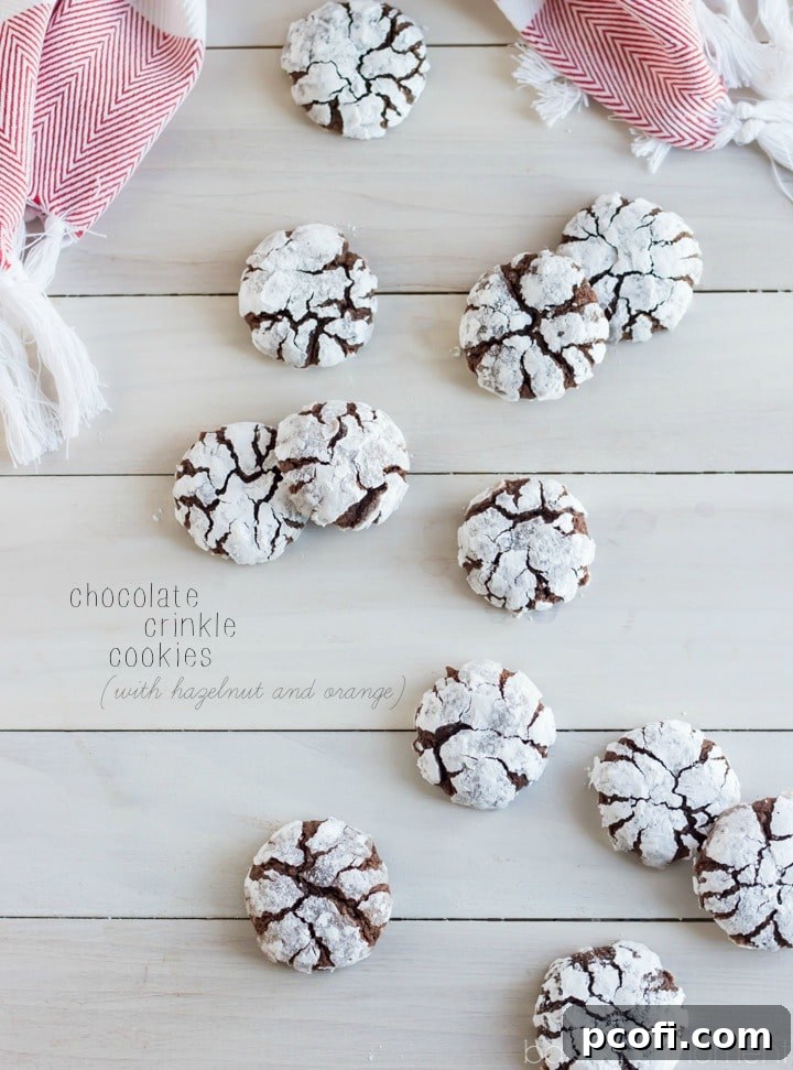 A close-up of a stack of Classic Chocolate Crinkle Cookies with Hazelnut and Orange, highlighting their soft, chewy texture and the perfect snowy crinkle finish, ready to be enjoyed as a festive treat.