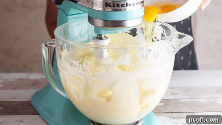 Adding eggs to cheesecake batter one at a time.