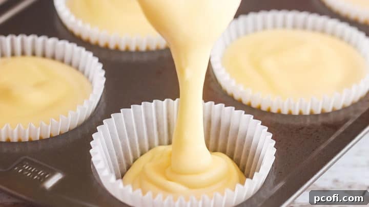 Pouring cheesecake batter into a cupcake pan.