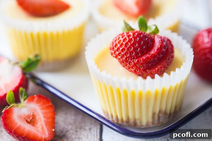 Cheesecake cupcakes on a tray with fresh strawberries.
