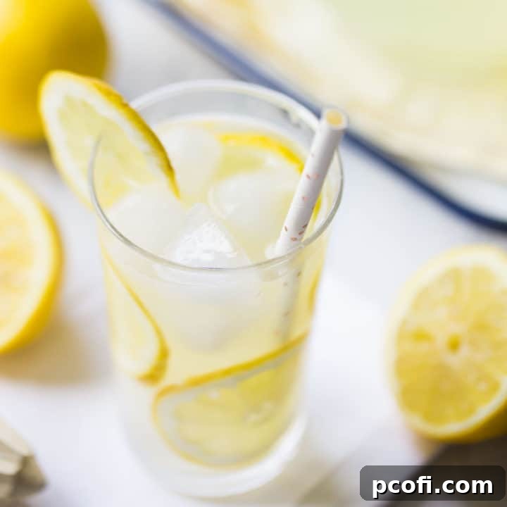 Tall glass of lemonade with ice and slices of fresh lemon.