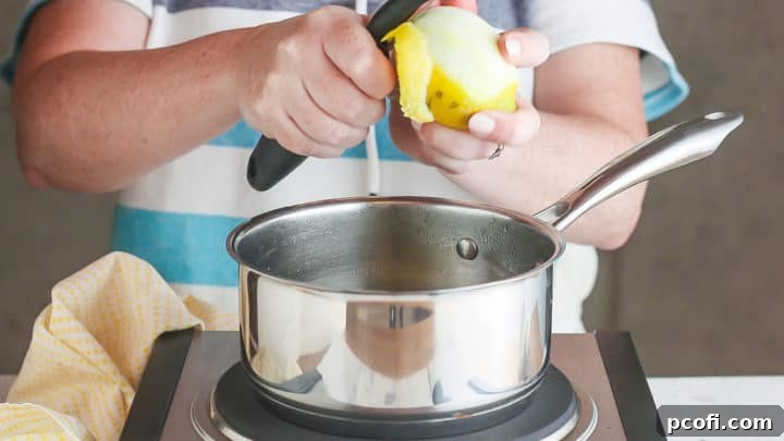Removing zest from a lemon with a vegetable peeler.