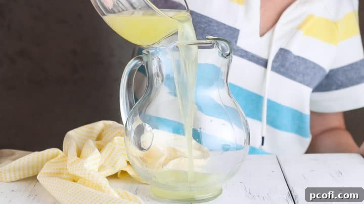 Pouring lemon juice into a glass pitcher.