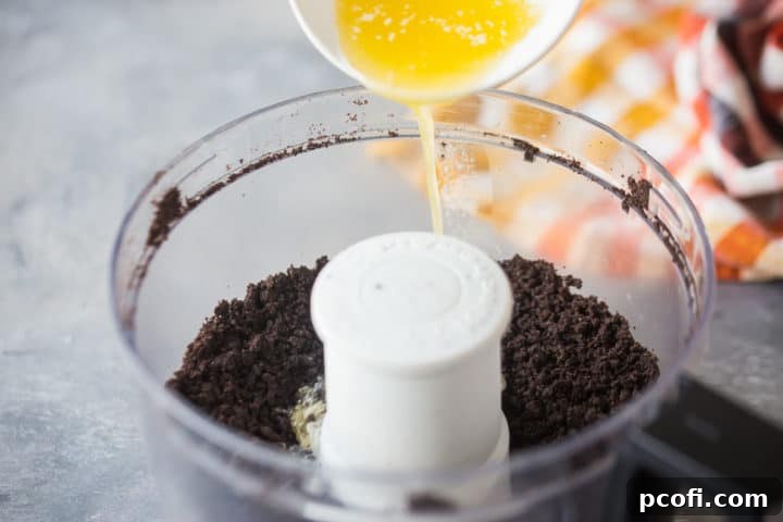 Pouring melted butter into Oreo cookie crumbs to make pie crust.