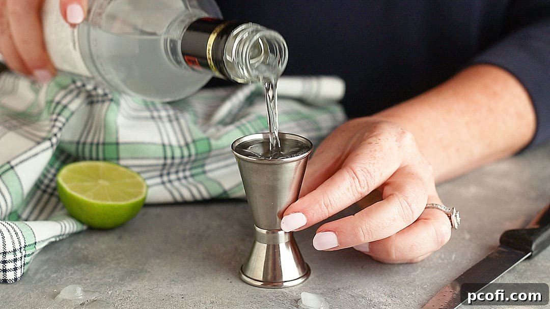 Measuring vodka into a stainless steel jigger.