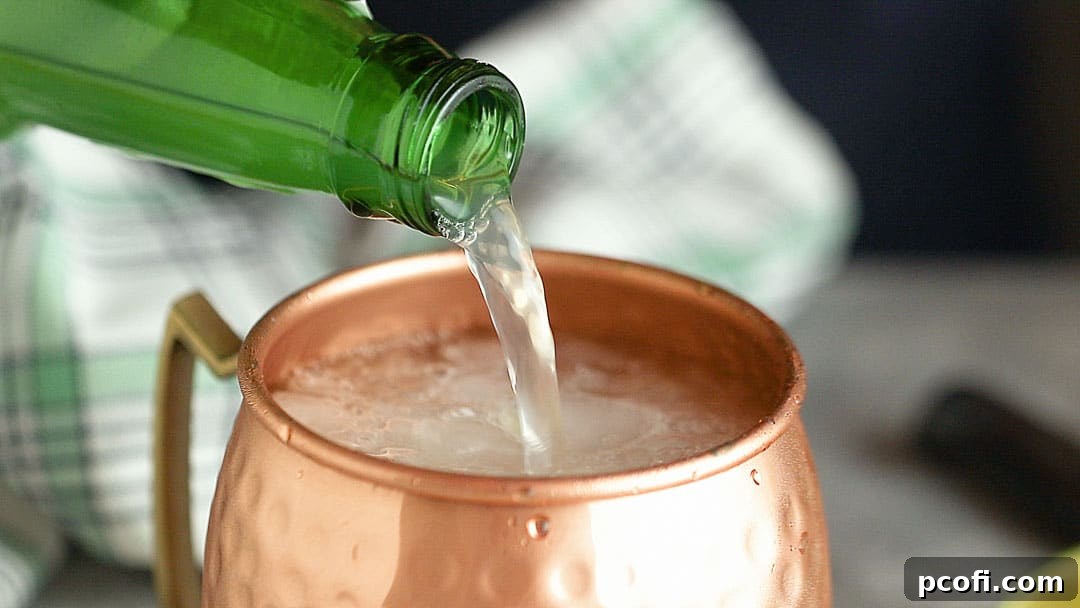 Pouring ginger beer into a Moscow Mule cocktail.