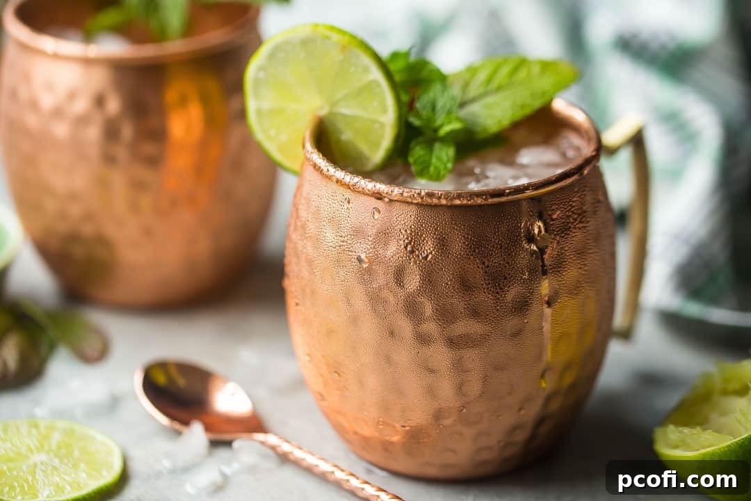 Two copper Moscow Mule mugs surrounded by crushed ice and fresh limes.