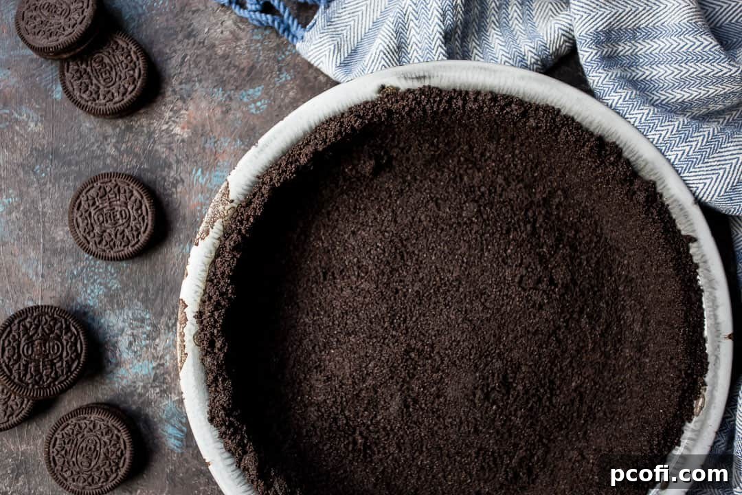 Oreo crust for pie or cheesecake, resting on a dark background with a blue towel, ready for a delicious dessert filling.