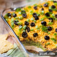 7-Layer dip in a square glass dish, with a green napkin.