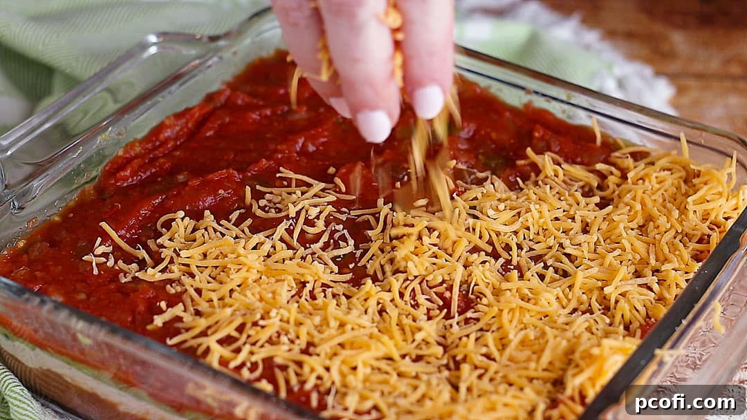 Generously sprinkling finely shredded cheese over the salsa layer, adding a rich, savory finish to the 7-Layer Dip.