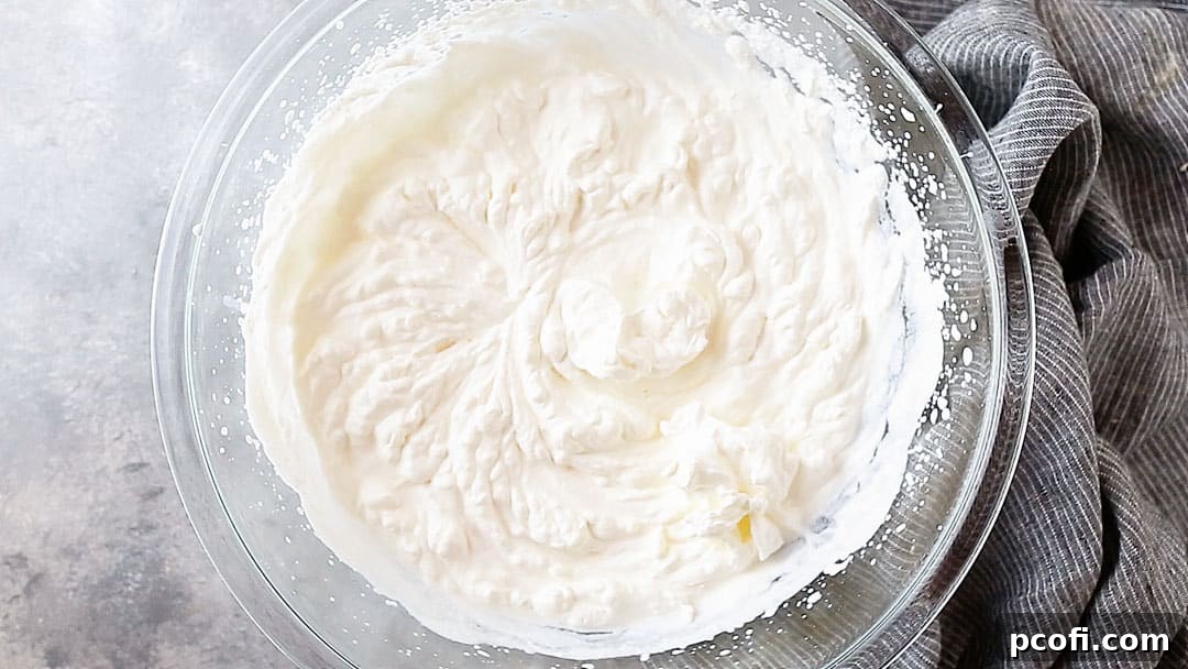 Overhead image of a bowl of stiffly whipped cream, on a gray background, showcasing the perfect consistency.